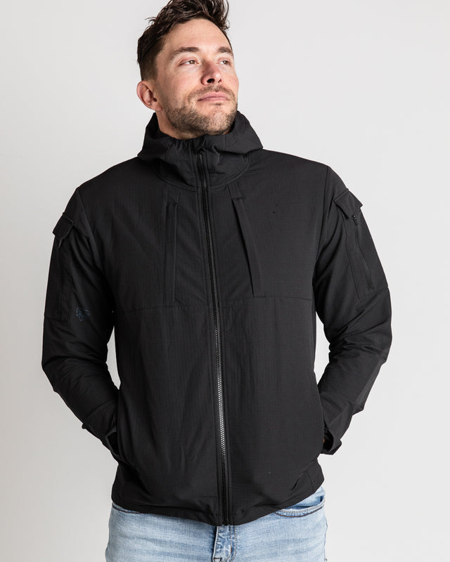 A person wearing a black ODIN Disc Golf jacket, showcasing the front with jacket zipped up.