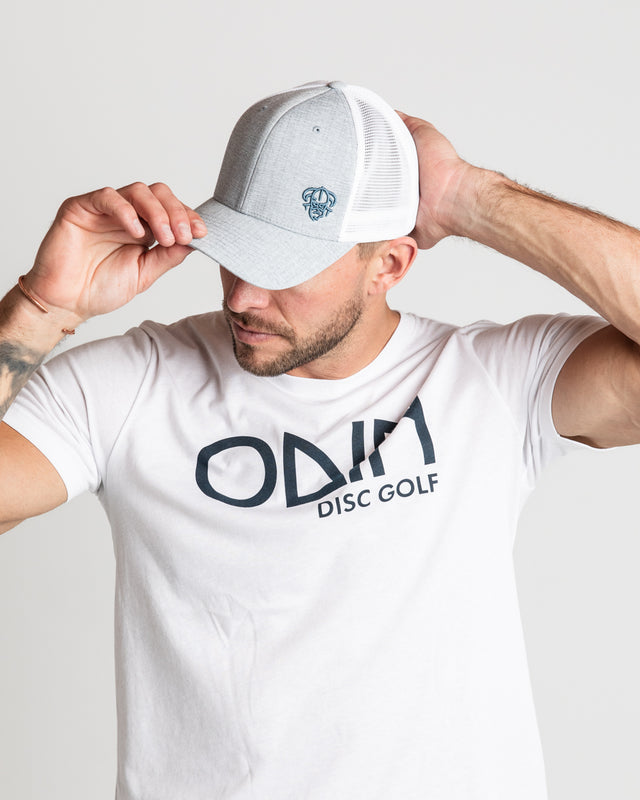 White Men's disc golf t-shirt front view of model, showcasing Two-tone grey and white snapback disc golf hat with Two-tone grey and white snapback disc golf hat with small steel blue embroidered logo | Odin Disc Golf