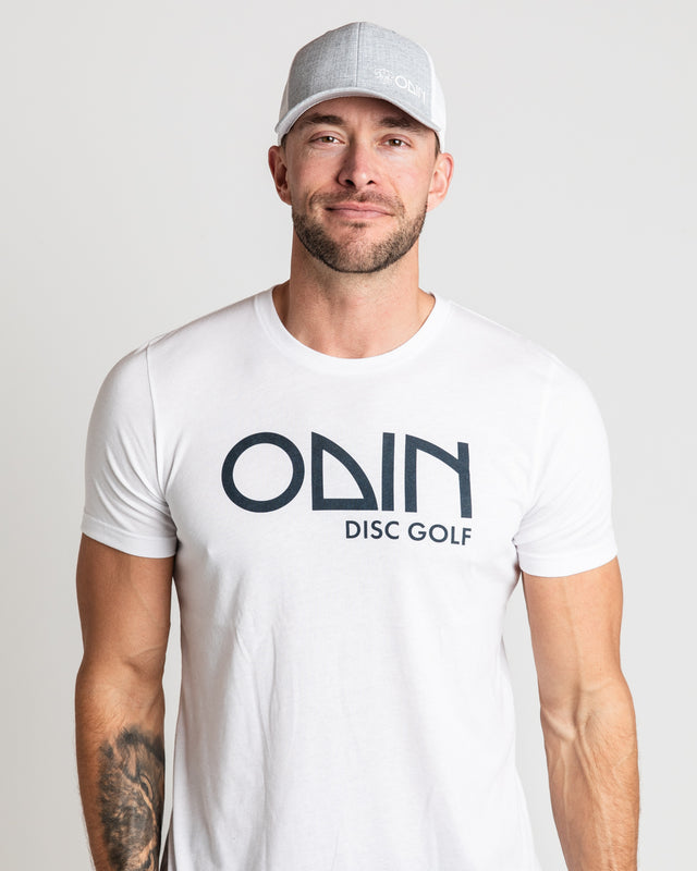 White Men's disc golf t-shirt  front view of model, showcasing Two-tone grey and white snapback disc golf hat with small white Odin vinyl print | Odin Disc Golf Apparel
